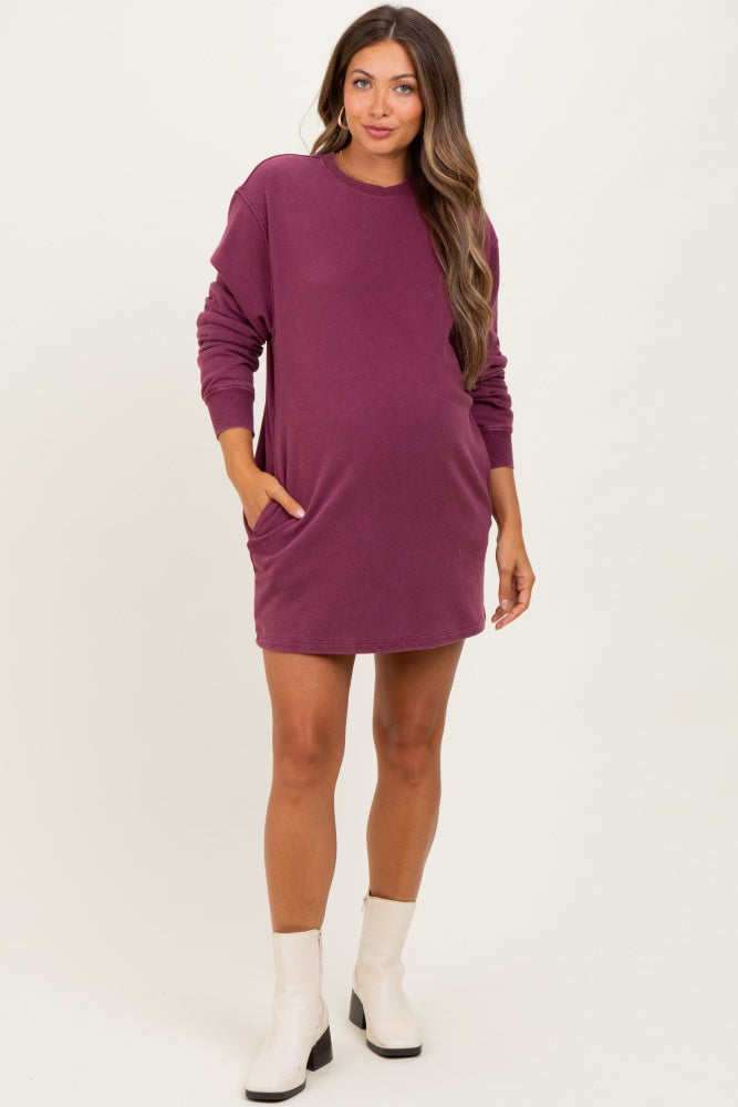 woman wearing a dark purple maternity sweatshirt dress with side pockets and long sleeves, showing her baby bump