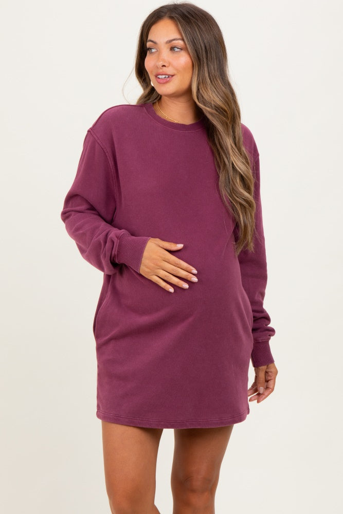 woman wearing a burgundy long sleeve maternity dress and holding her baby bump