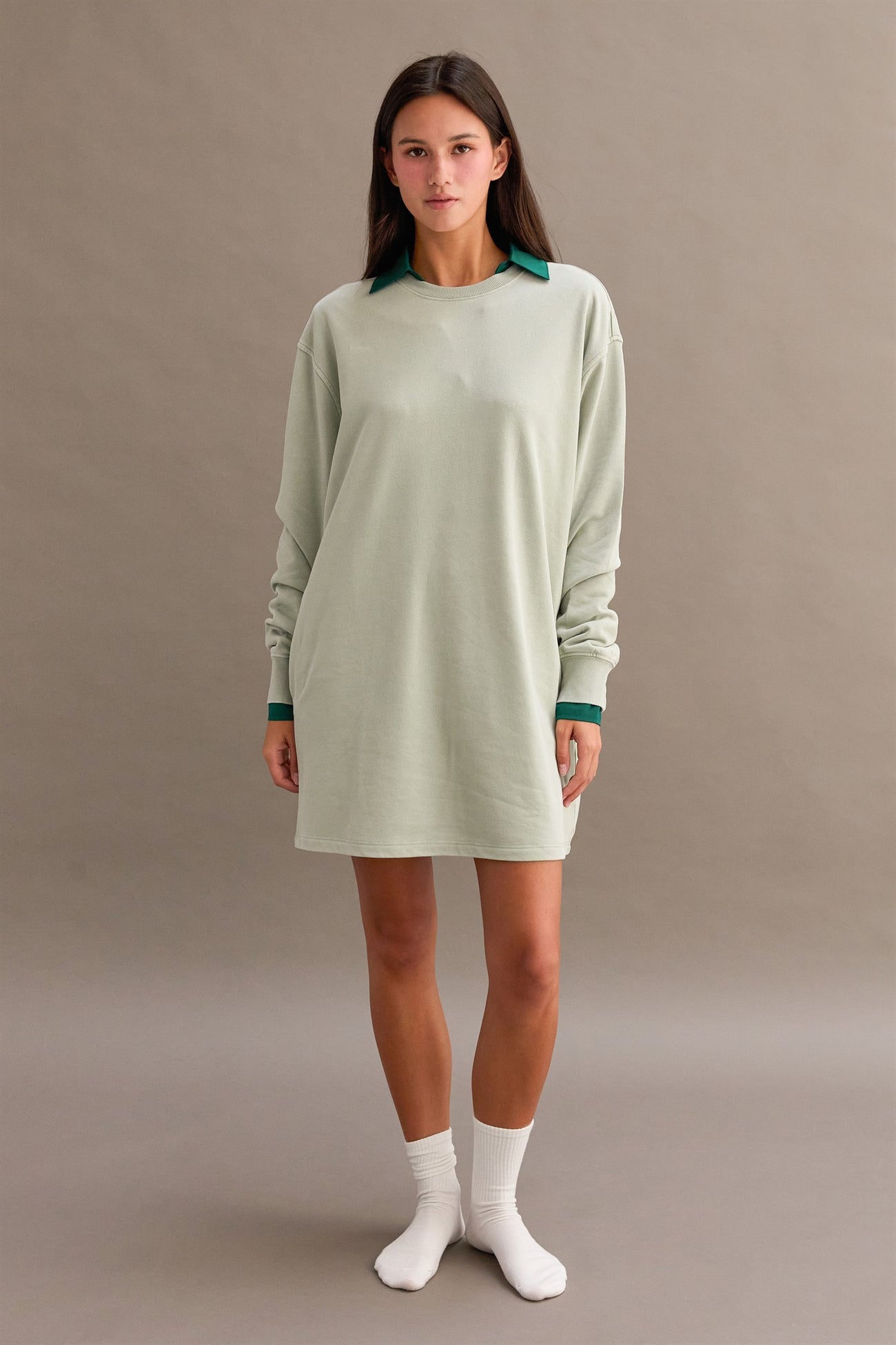 woman wearing a green oversized long sleeve dress with a dark green collar and white socks