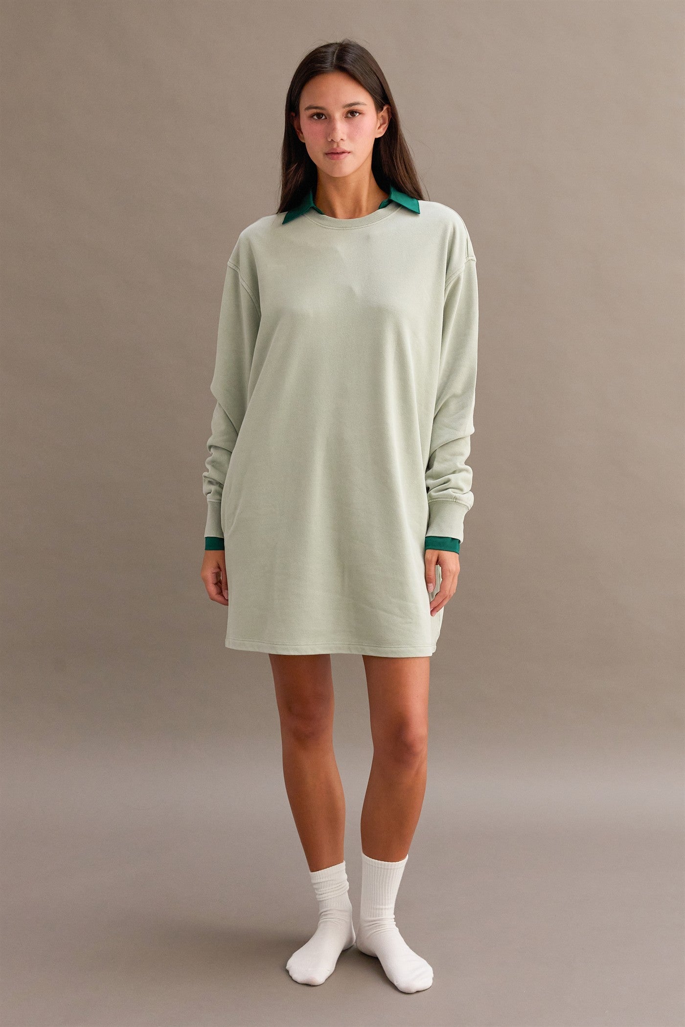 woman wearing a green oversized long sleeve dress with a dark green collar and white socks