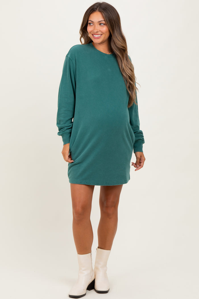 woman wearing a dark green maternity sweatshirt dress with long sleeves and a visible baby bump
