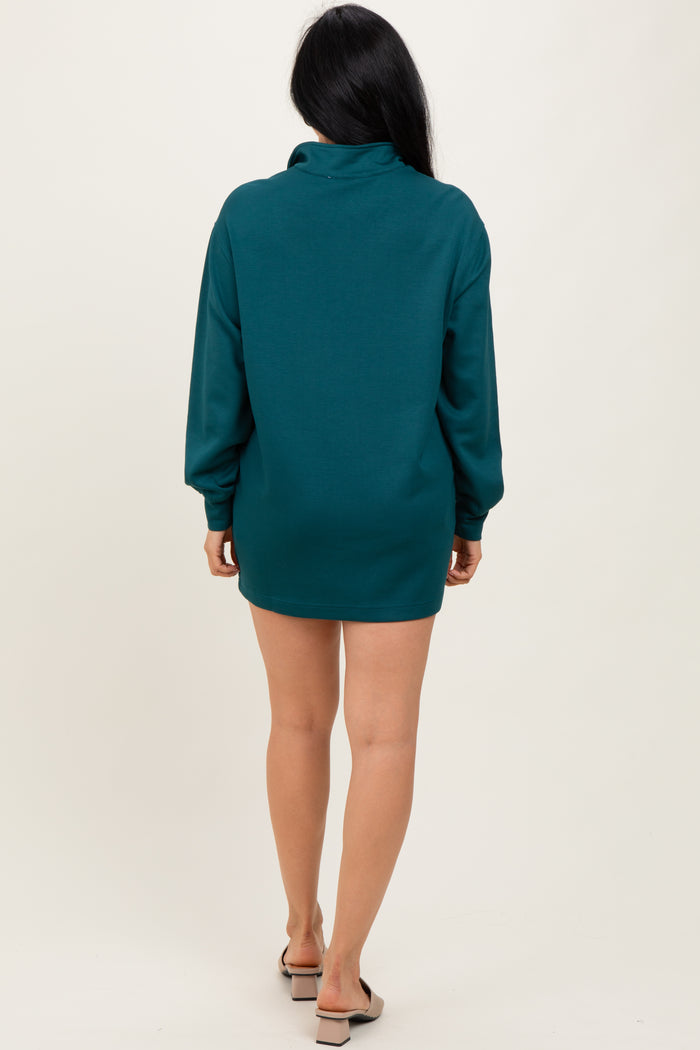 woman wearing a teal oversized sweater dress with long sleeves, shown from the back