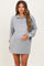 woman wearing a gray maternity quarter-zip sweatshirt dress and holding her baby bump