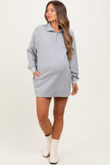 woman wearing a gray maternity zip-up dress with long sleeves and side pockets, showcasing her baby bump