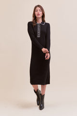 woman wearing a black ribbed midi dress with a white collared neckline and long sleeves, styled with black ankle boots