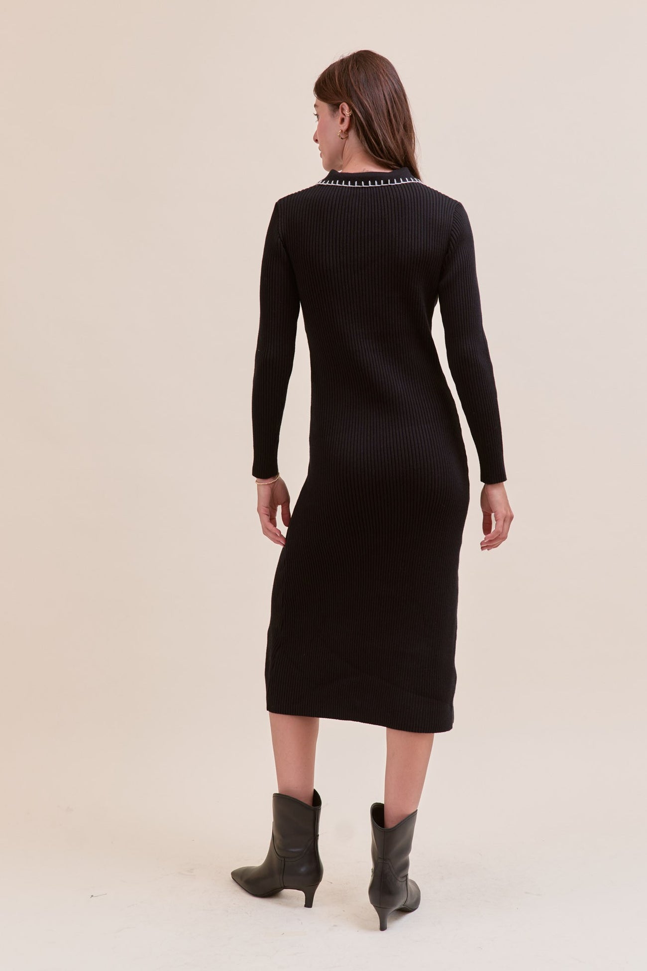 woman wearing a black ribbed long sleeve midi dress with a fitted silhouette and boots