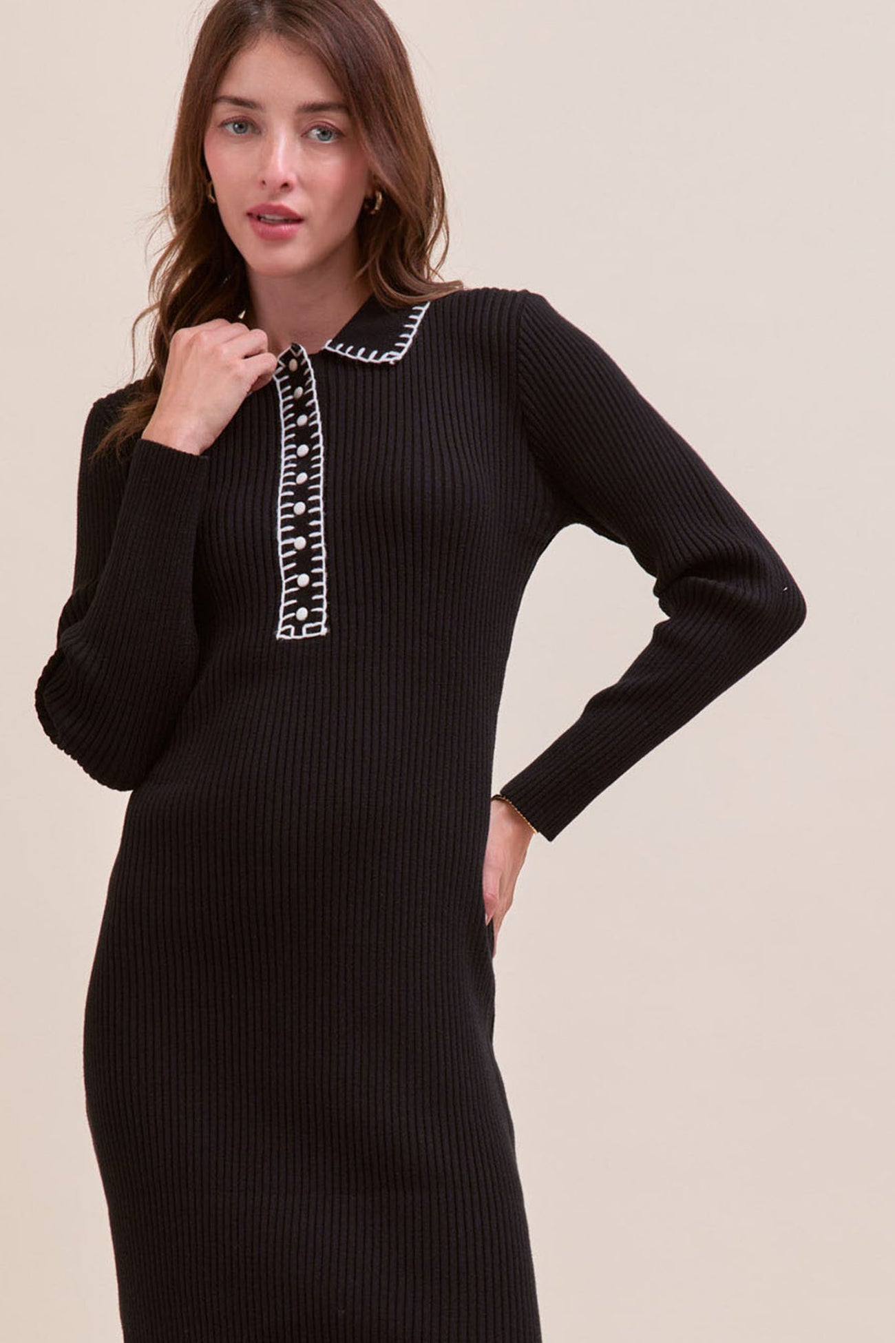 woman wearing a black ribbed sweater dress with a white collar and button detail