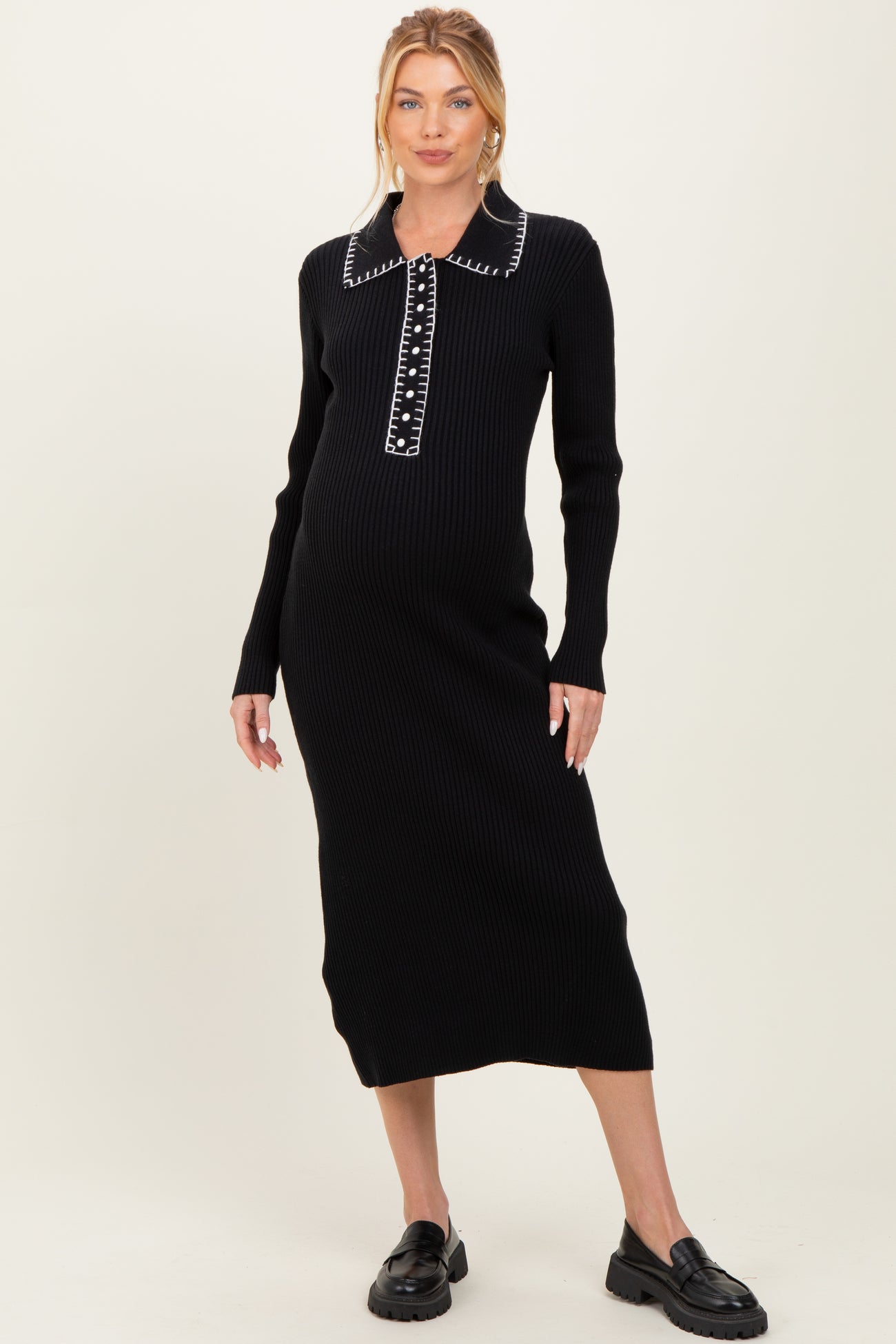 woman wearing a black ribbed maternity dress with a button-up collar and long sleeves, showing her baby bump
