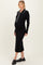 woman wearing a black ribbed maternity dress with a collar and long sleeves, showing her baby bump