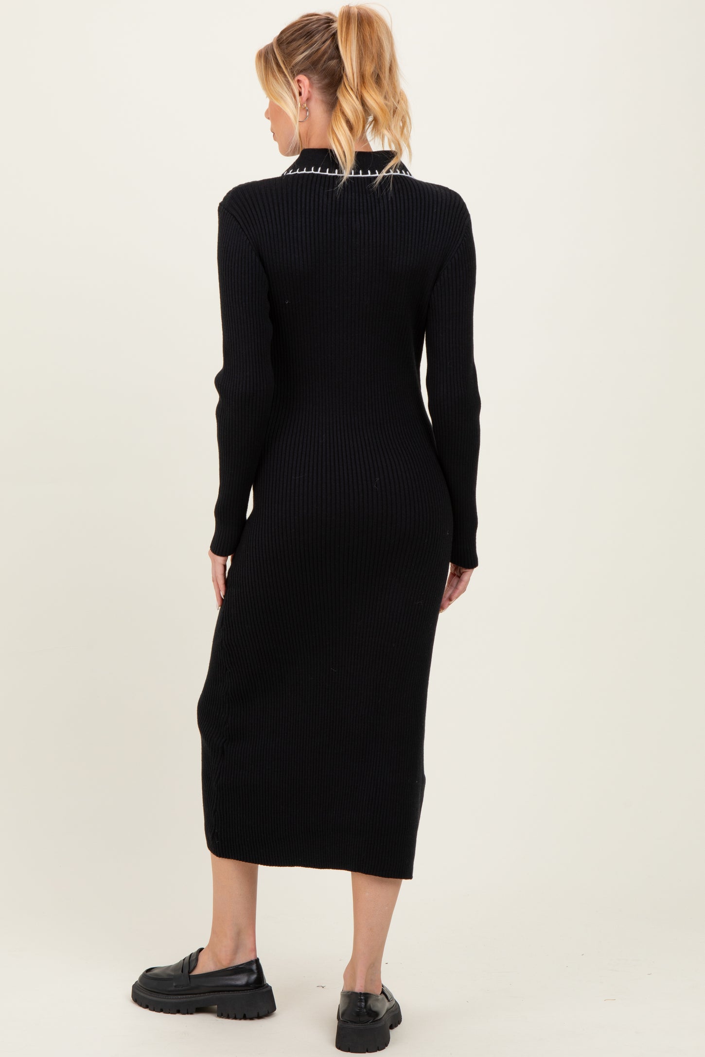 woman wearing a black ribbed maternity dress with long sleeves and a fitted silhouette, showing her baby bump