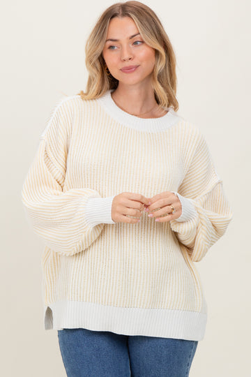 woman wearing a beige and white striped oversized sweater with balloon sleeves and side slits, smiling at the camera