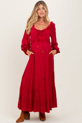 woman wearing a red maternity maxi dress with puff sleeves and a drawstring waist, showing her baby bump