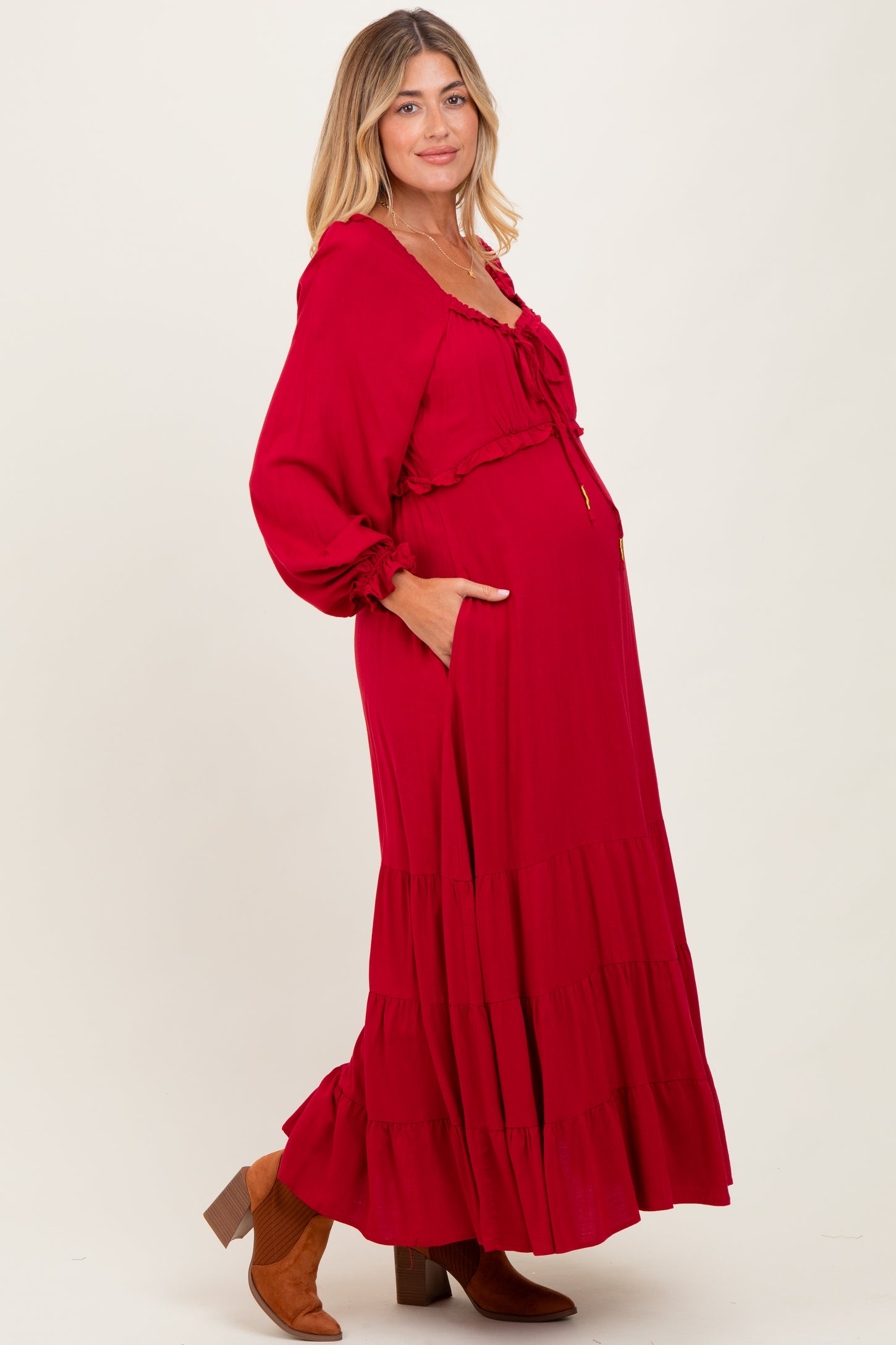 woman wearing a red long sleeve maternity maxi dress with a ruffle hem and a visible baby bump