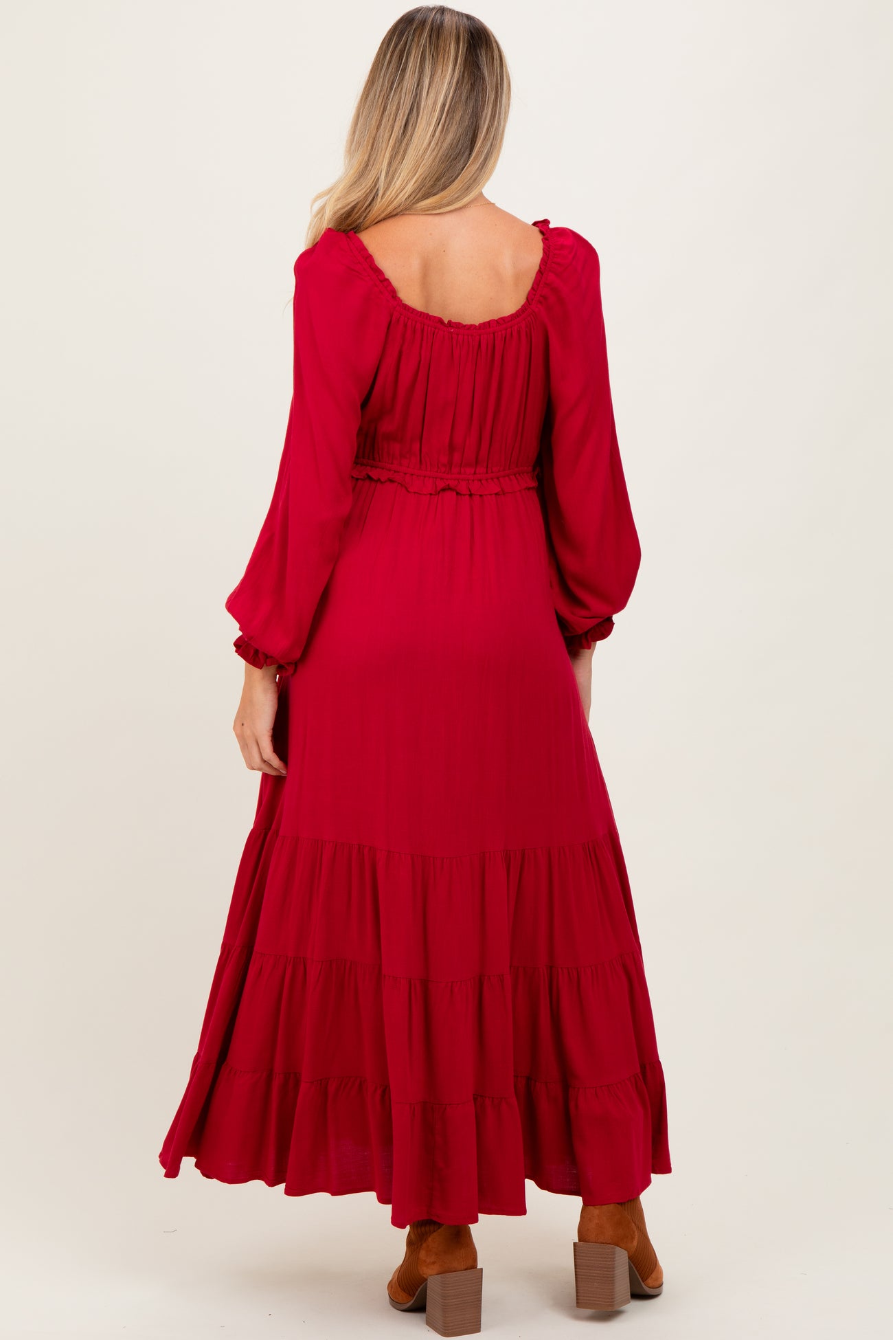 woman wearing a long red maternity dress with tiered ruffles and long sleeves, showing her back