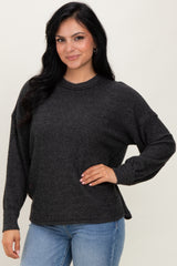 woman wearing a dark gray oversized sweater with long sleeves and side slits, paired with light blue jeans