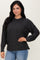 woman wearing a dark gray oversized sweater with long sleeves and side slits, paired with light blue jeans