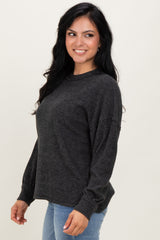 woman wearing a dark grey oversized sweater with long sleeves and a relaxed fit, paired with light blue jeans