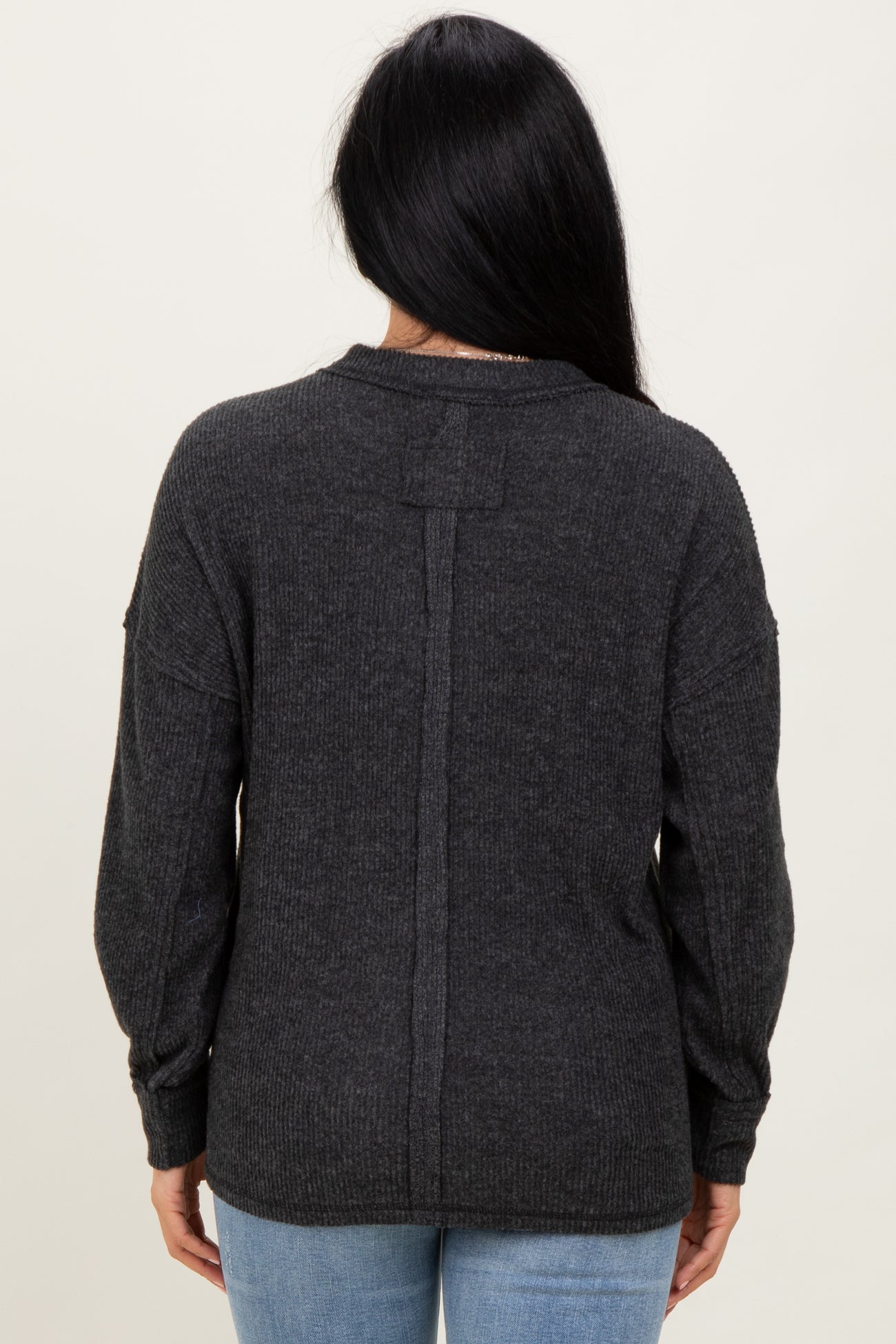 woman wearing a dark gray oversized sweater with a back seam detail and balloon sleeves