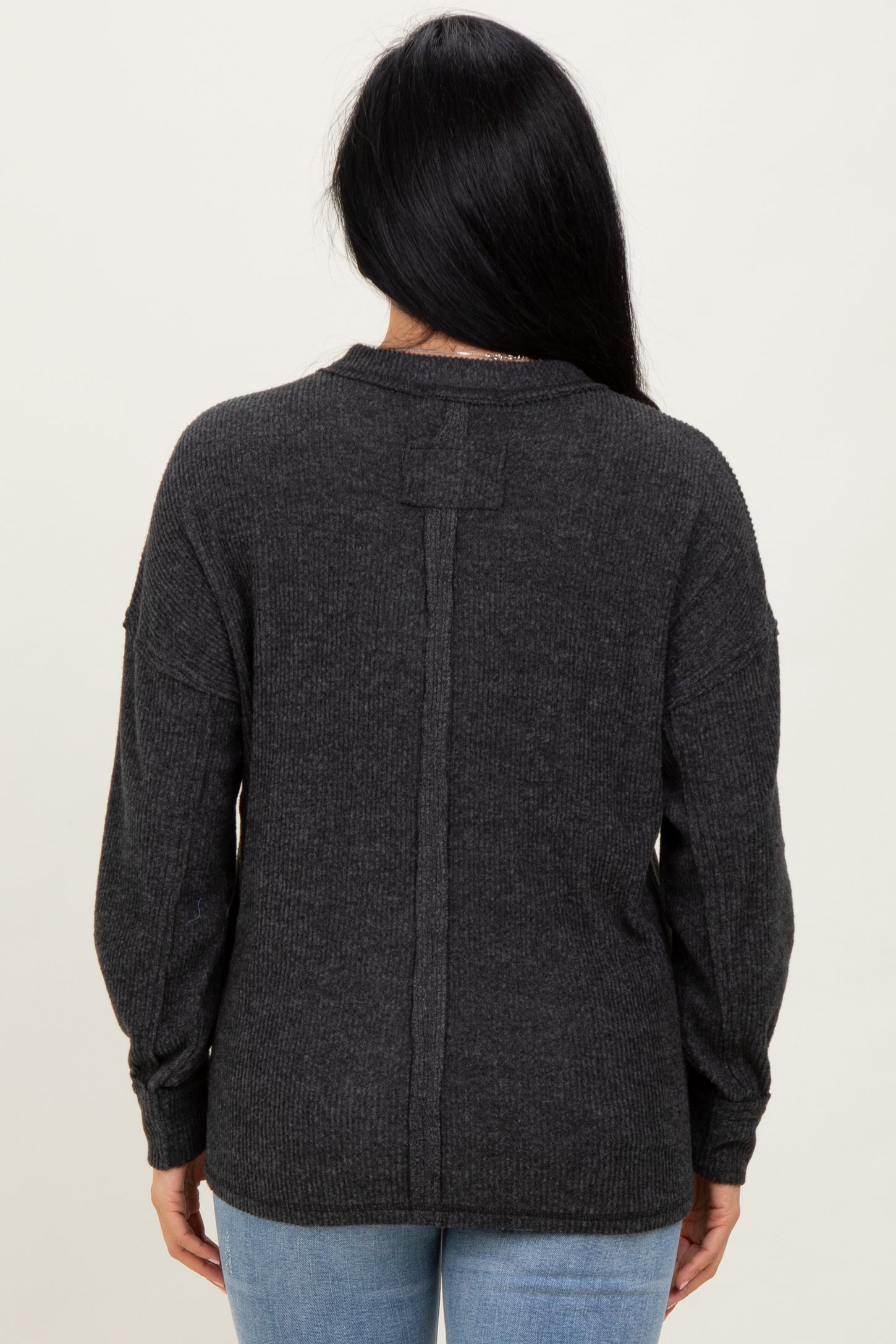 woman wearing a dark gray oversized sweater with a back seam detail and balloon sleeves