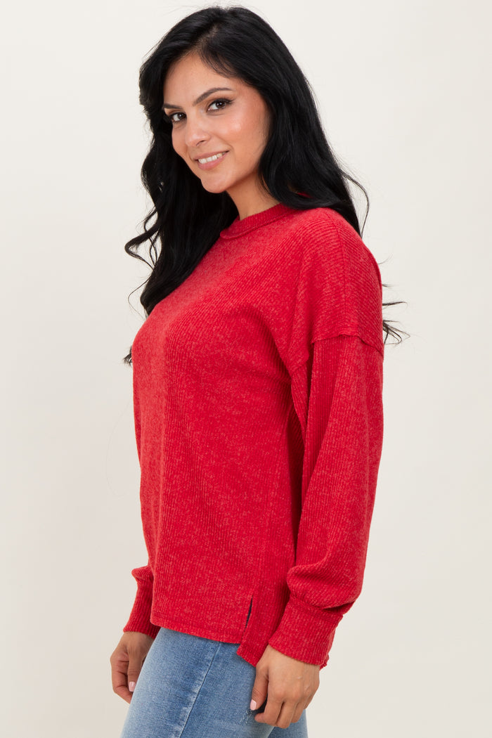 woman wearing a red long sleeve sweater with a relaxed fit and side slits, smiling while standing sideways