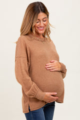 woman wearing a brown ribbed maternity sweater and holding her baby bump