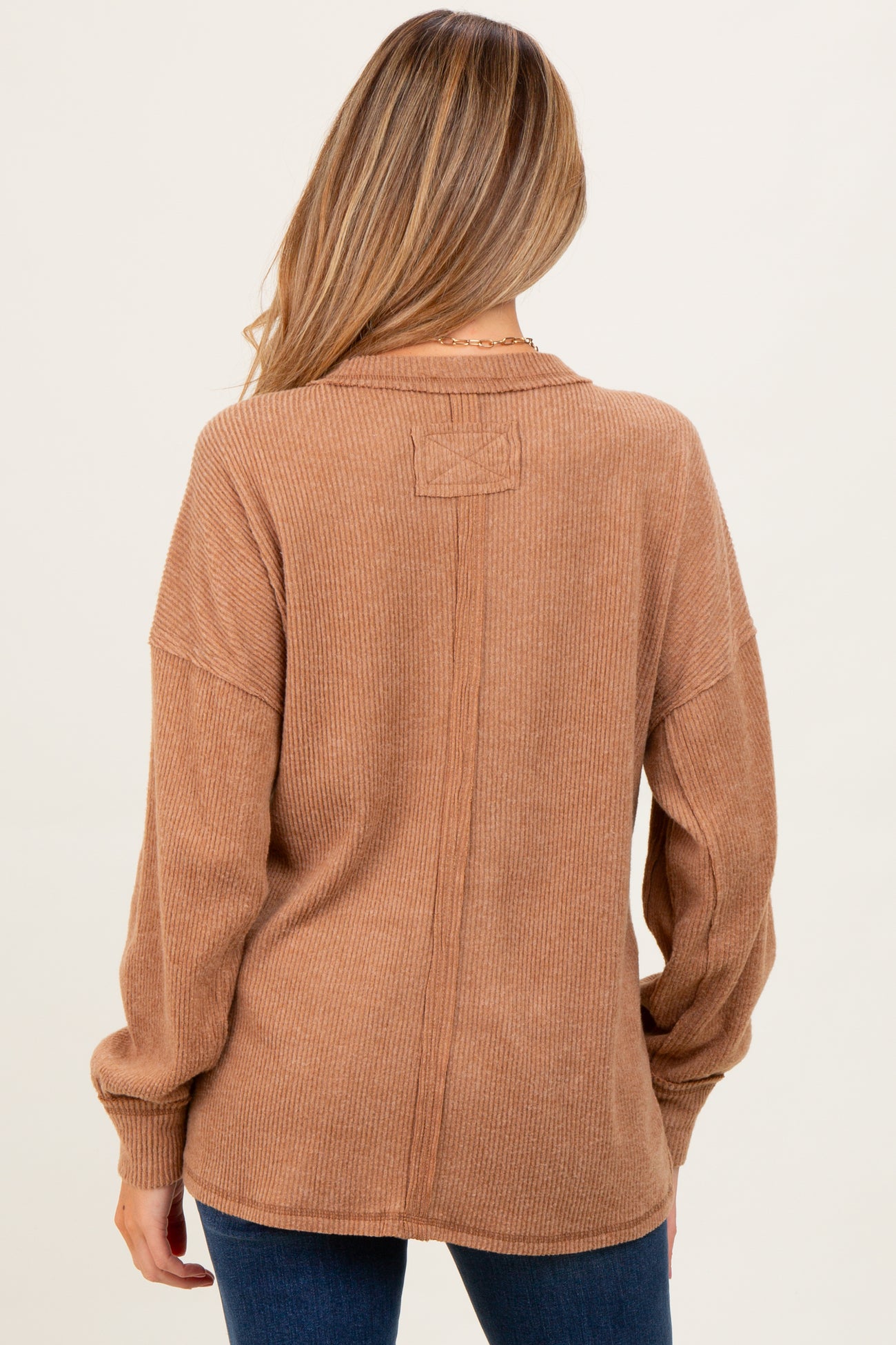 woman wearing a soft brown ribbed maternity top with dropped shoulders and long sleeves, viewed from the back