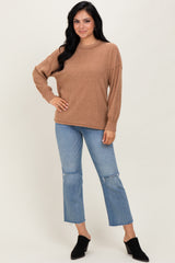 woman wearing a brown oversized sweater with long sleeves and blue distressed denim cropped jeans