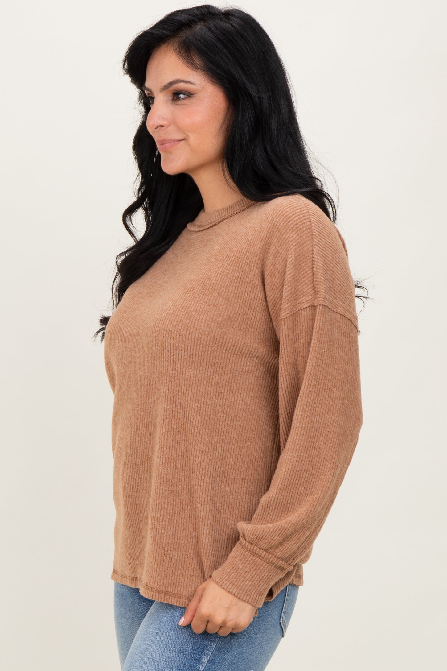 woman wearing a brown ribbed long sleeve top with a relaxed fit and round neckline