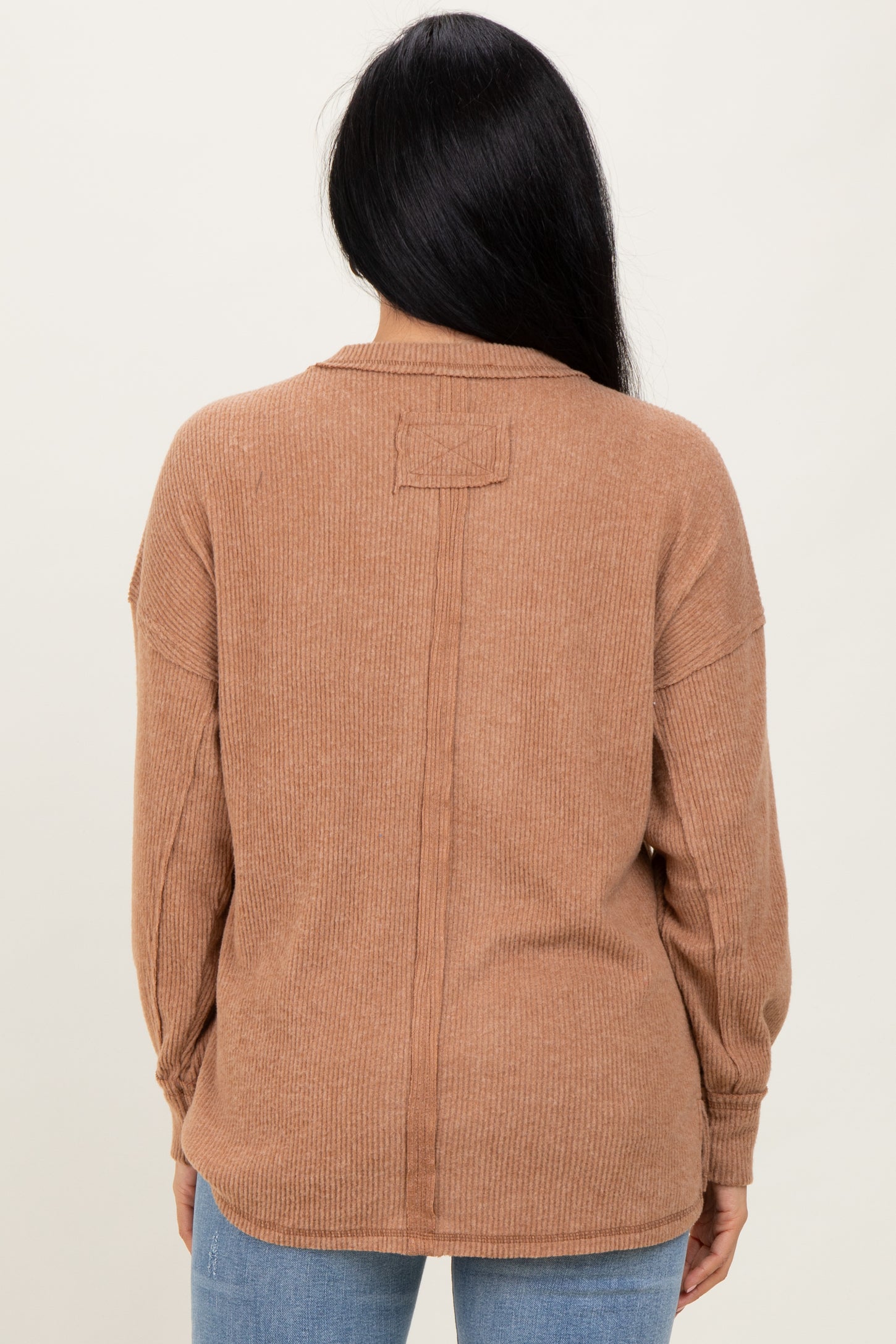 woman wearing a brown ribbed long sleeve sweater, showing the back view with a relaxed fit and dropped shoulders