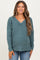 woman wearing a teal maternity v-neck sweater with ribbed texture and long sleeves, smiling with a baby bump visible
