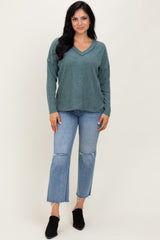 woman wearing a teal v-neck sweater with relaxed fit and distressed straight leg jeans, paired with black ankle boots