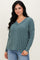 woman wearing a teal v-neck knit sweater with long sleeves and a relaxed fit, paired with light blue jeans