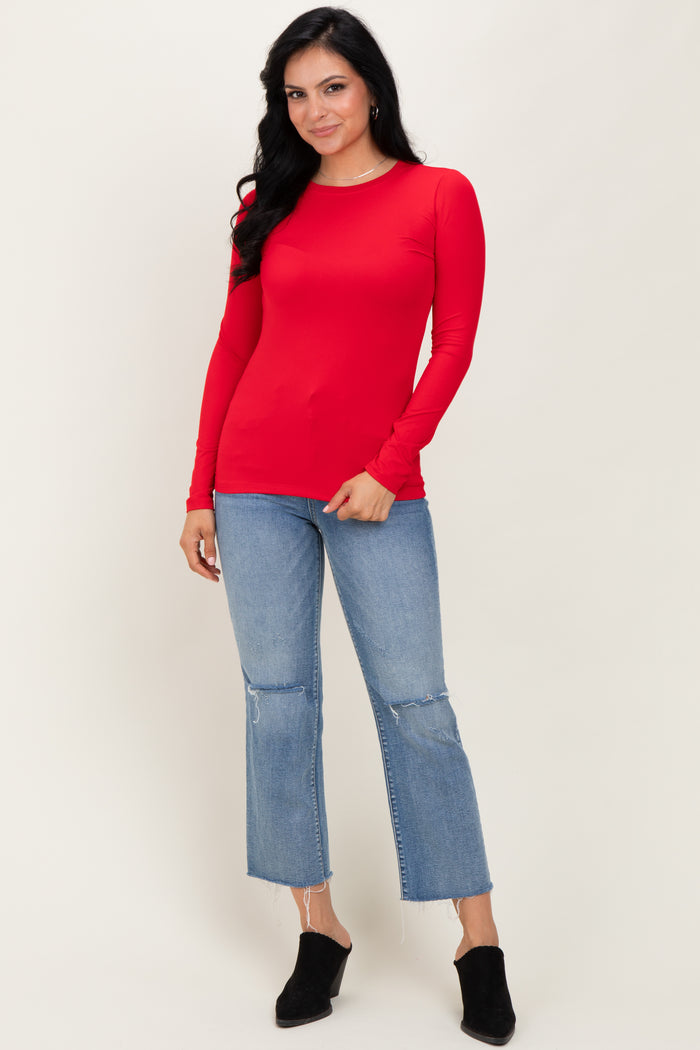 woman wearing a long sleeve red top paired with light wash cropped jeans and black heeled mules