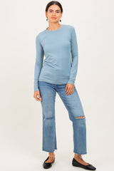 woman wearing a light blue long sleeve top paired with distressed jeans and black flats