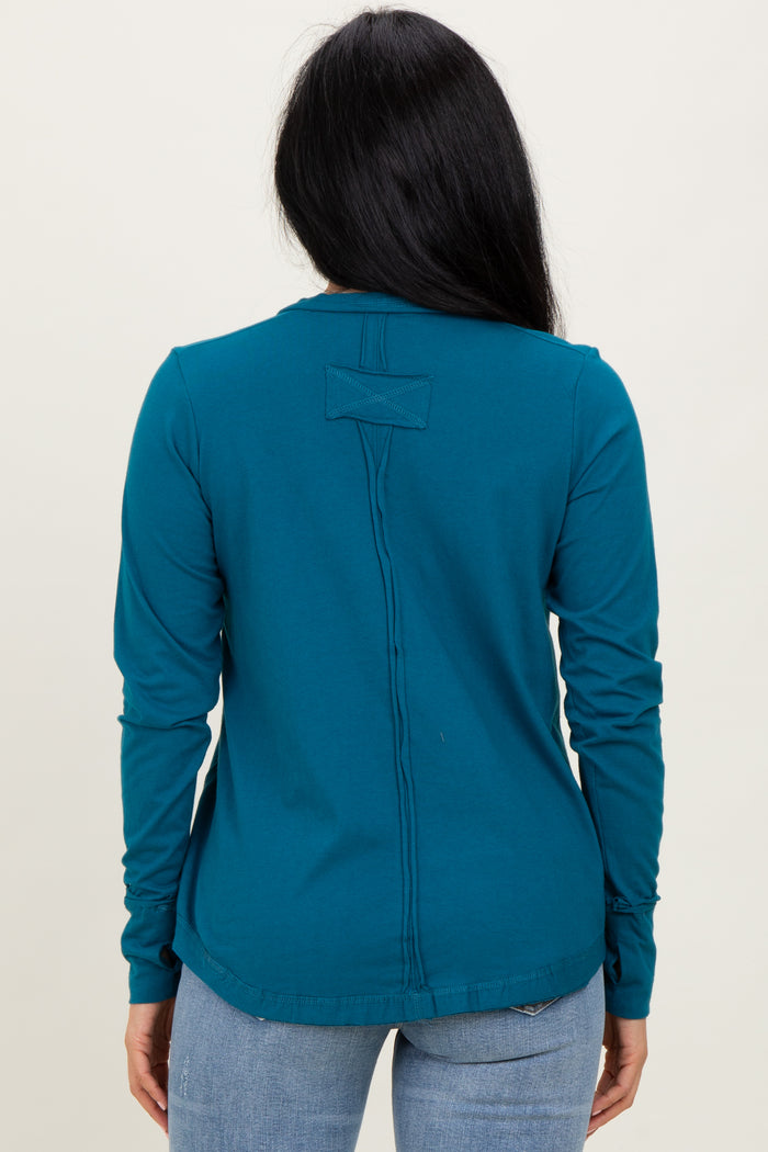 woman wearing a teal long sleeve top with a back seam detail, styled with light blue jeans