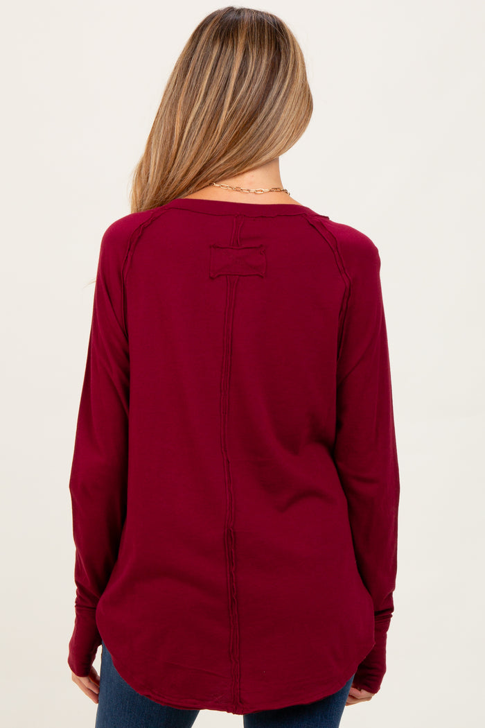 woman wearing a burgundy long sleeve maternity top with a back detail and relaxed fit