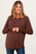 woman wearing a brown long sleeve maternity top and showing her baby bump