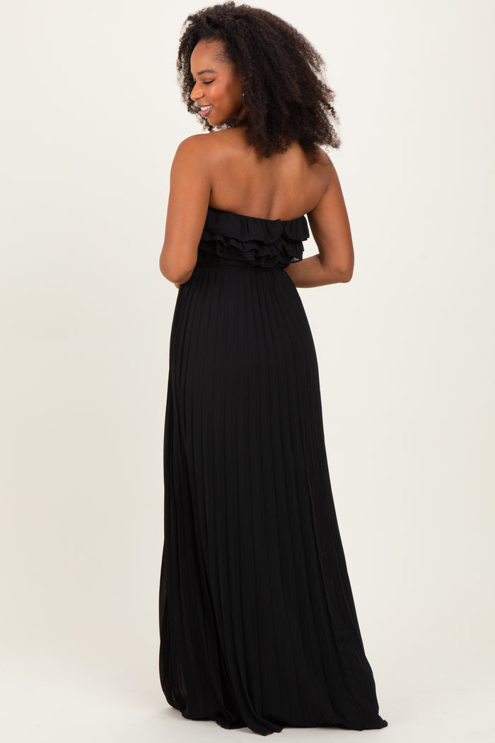woman wearing a black strapless maxi dress with ruffle detailing and pleated fabric, viewed from the back