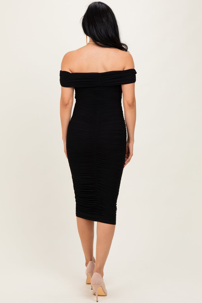 woman wearing a black off-the-shoulder bodycon dress with ruched detailing and a form-fitting silhouette