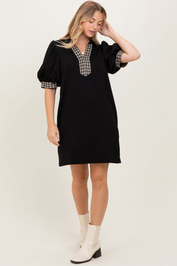 woman wearing a black puff sleeve dress with a checkered collar and cuffs, styled with beige ankle boots