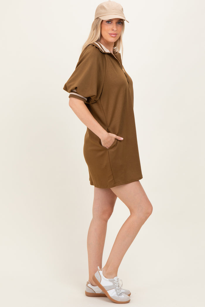 woman wearing a brown polo-style dress with short sleeves and pockets, paired with a beige cap and white sandals