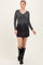 woman wearing a black ribbed long sleeve top and a black button-front mini skirt, paired with knee-high black boots