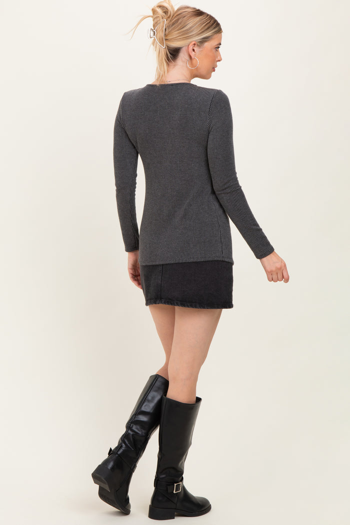 woman wearing a dark gray ribbed long sleeve top, paired with a black denim skirt and tall black boots