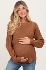 woman wearing a rust ribbed maternity sweater and holding her baby bump