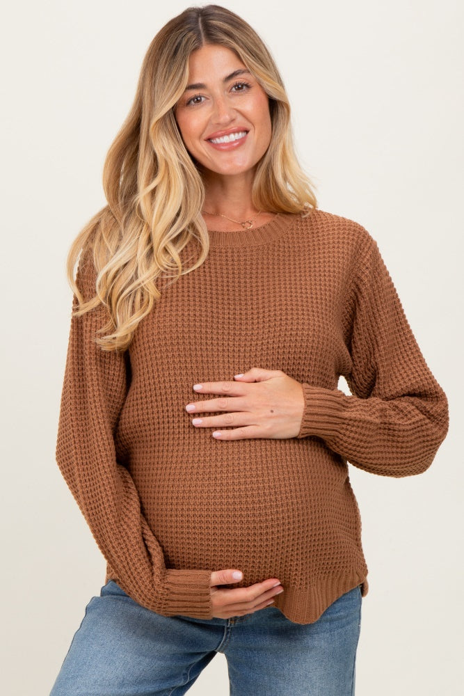 woman wearing a rust ribbed maternity sweater and holding her baby bump