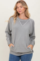 woman wearing a gray long sleeve sweatshirt with a relaxed fit and front pockets, styled with a round neckline