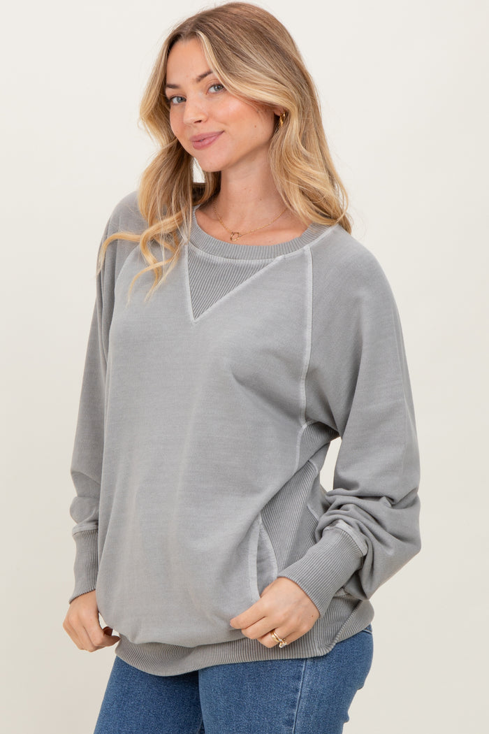 woman wearing a gray oversized sweatshirt with a v-neck and long sleeves, paired with blue jeans