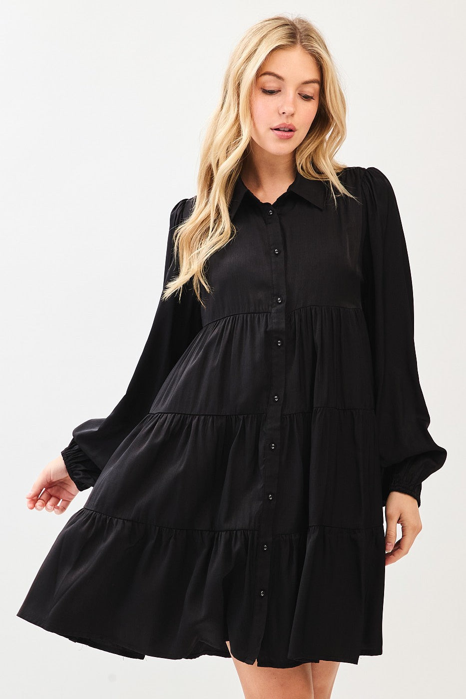 woman wearing a black long sleeve tiered dress with buttons and a collared neckline