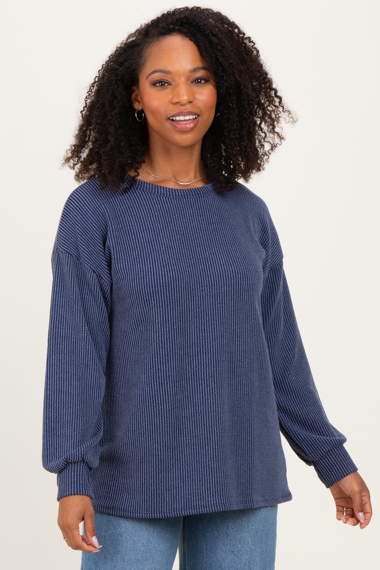 woman wearing a navy blue ribbed long sleeve sweater with a relaxed fit and balloon sleeves