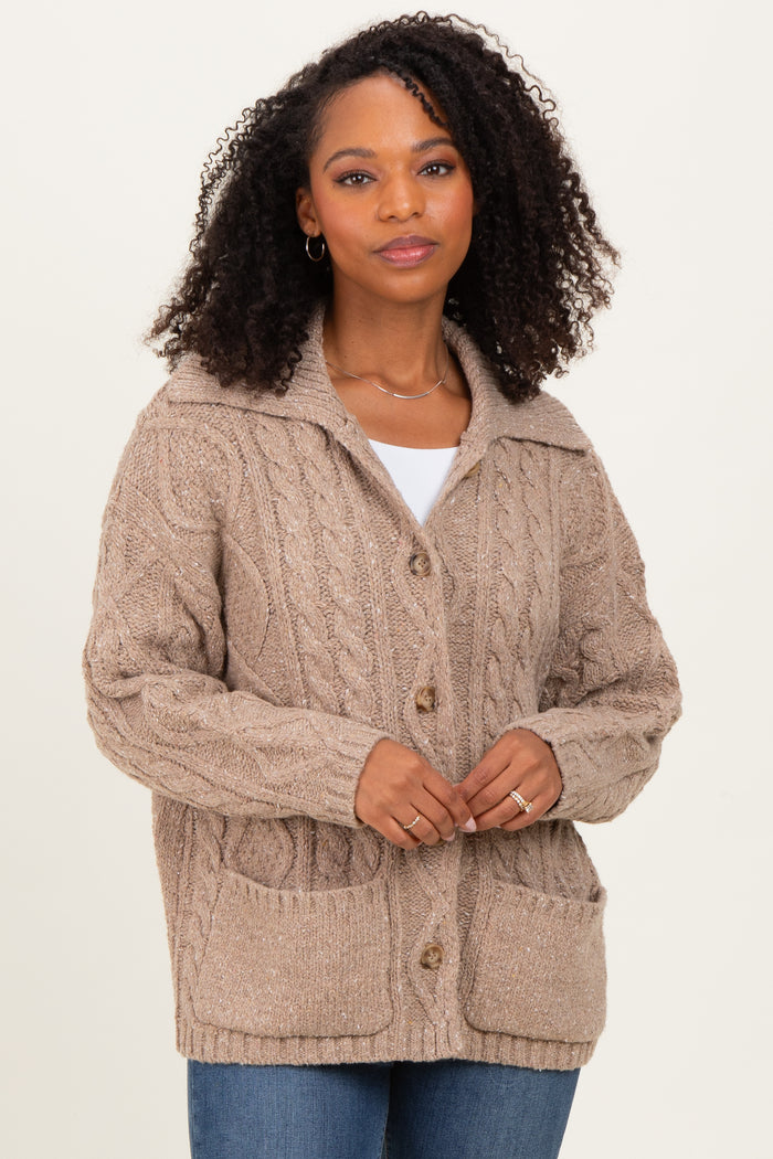 woman wearing a beige cable knit cardigan with a collar and pockets, paired with a white top and blue jeans